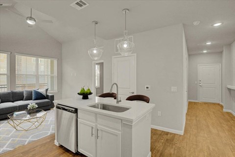 a white kitchen with a sink and a living room with a couch